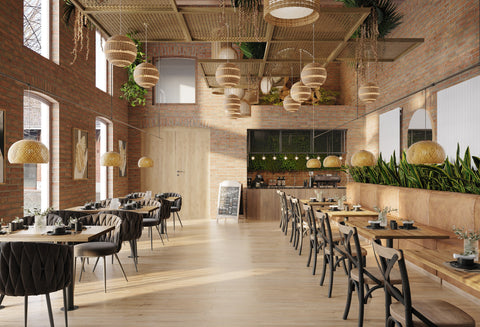 Woven wicker pendant lights with warm golden hue hang above solid wood dining tables with pole leg for cafes and restaurants