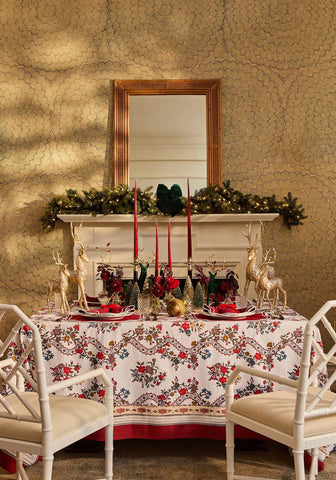 A festive sommerset scroll red cotton tablecloth with white base gold deer and holiday floral decorations