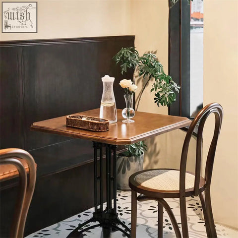 A solid wood sonnet dining chair next to a square wooden table with dark brown finish and black metal legs