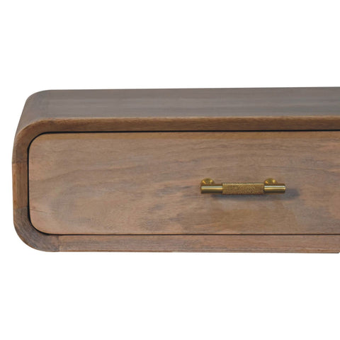 A sleek light brown wooden drawer with a brushed brass textured handle in a wall mounted bedside table