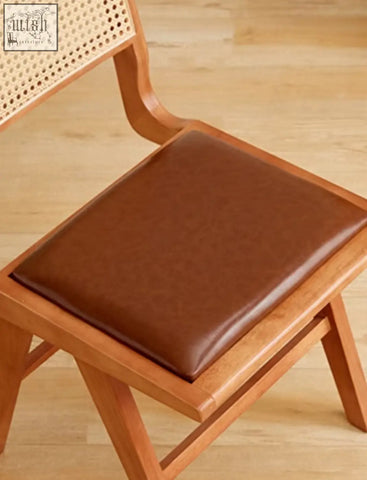 Brown leather seat cushion on sophia rattan dining chair with wooden frame and cane backrest for dining use