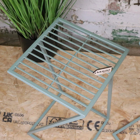 A mint green metal folding side table with a grid pattern and x-shaped legs from soraya green garden table set