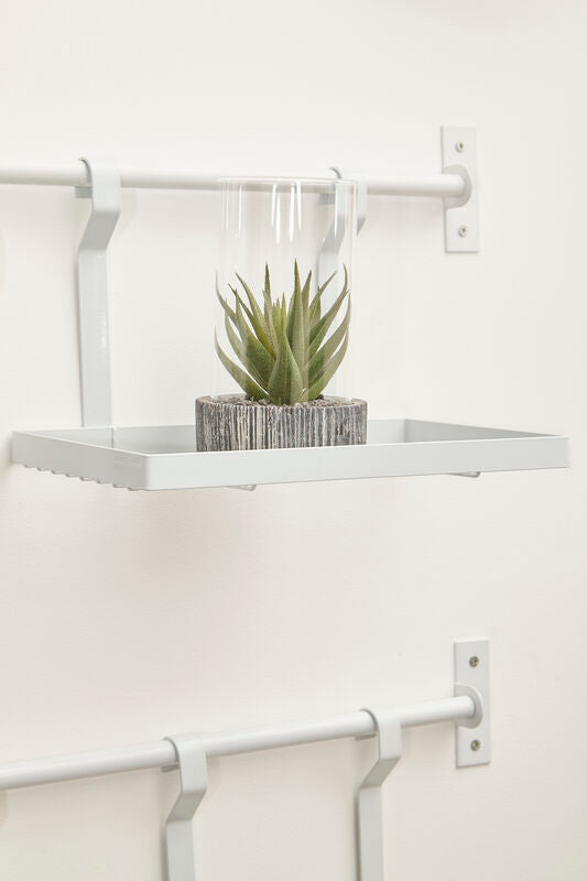 White iron single shelf storage rack by sorello with a white metal shelf and a green succulent in a glass dome