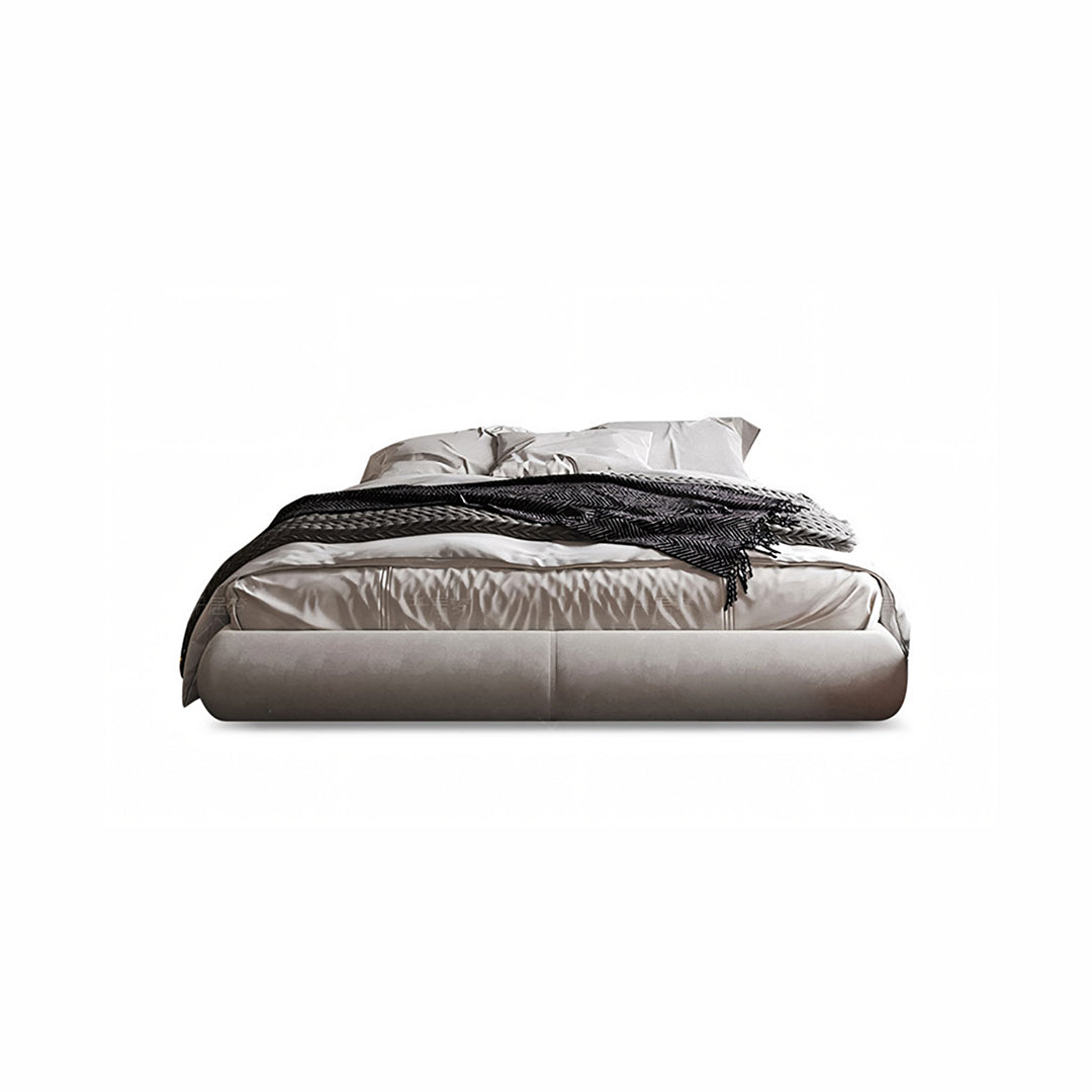 A soren king size bed with a sleek gray velvet low-profile frame, matching pillows, and a black textured throw blanket