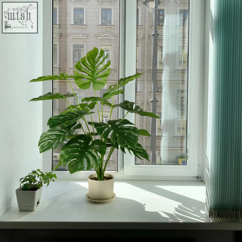 A lush green fake monstera plant in a beige pot perfect as a tropical palm tree for indoor outdoor decor