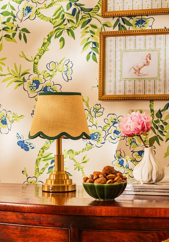 A brass table lamp with a beige scalloped fabric shade and green trim for spicing up your space