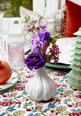 White ceramic garlic bud vase with vertical ridges holding purple and pink flowers to spice up your space