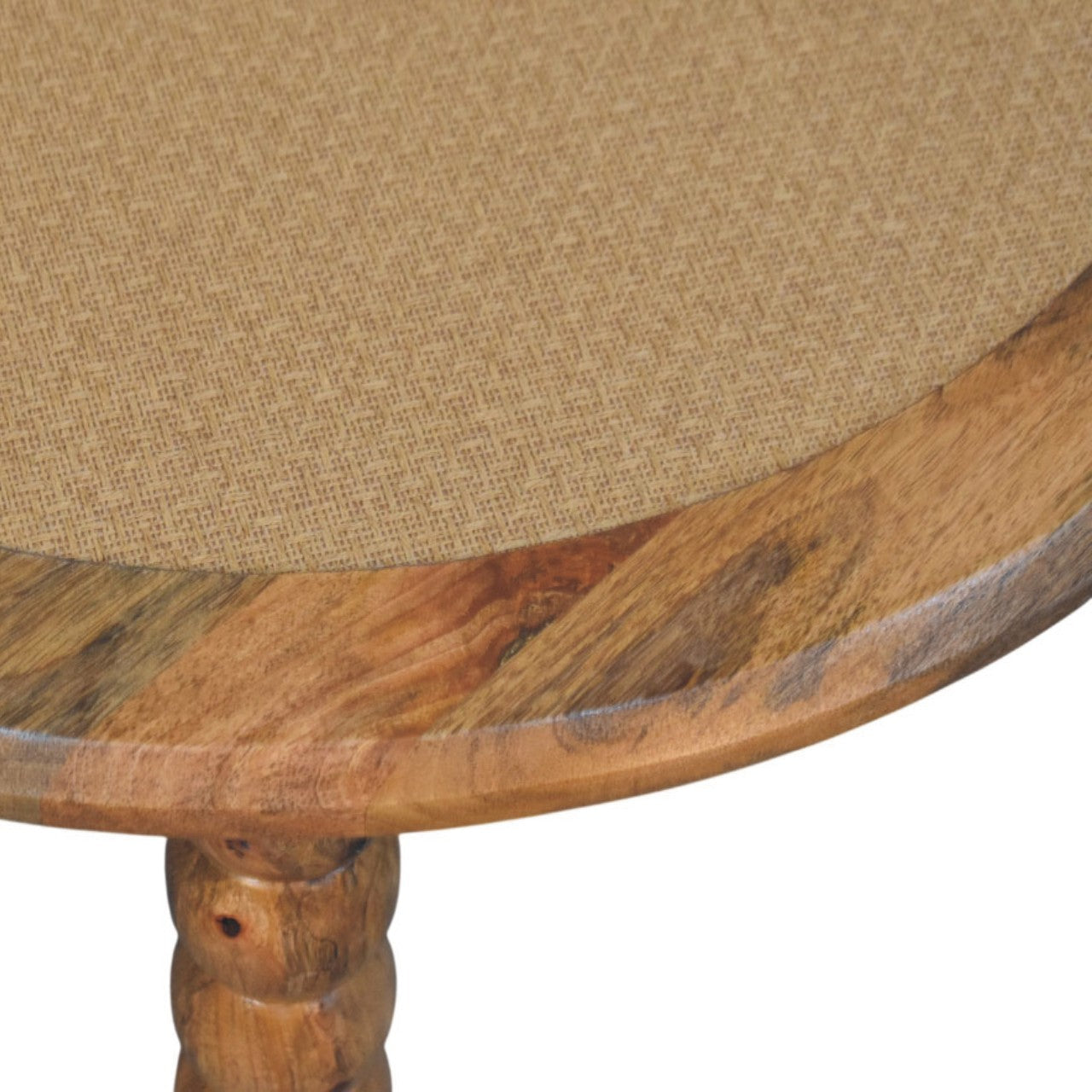 A spindle rattan coffee table with a round wooden rustic finish and beige woven fabric top