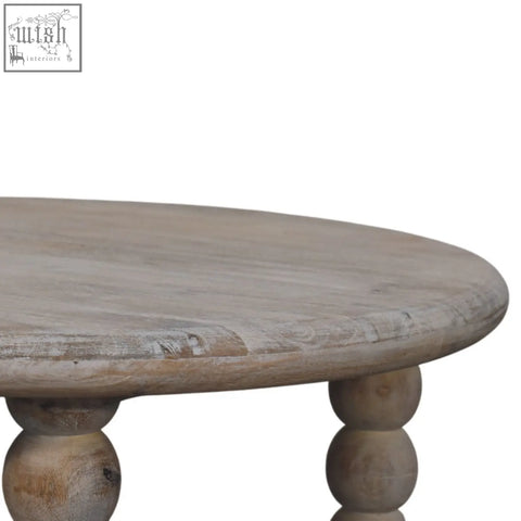 A round light-colored spindle salted oak coffee table with distressed finish and turned ball legs in solid mango wood