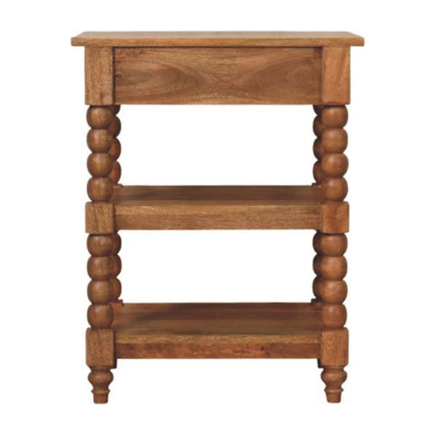 Light brown wooden spindle side table with golden teak finish, one drawer, and two open shelves with turned bead legs