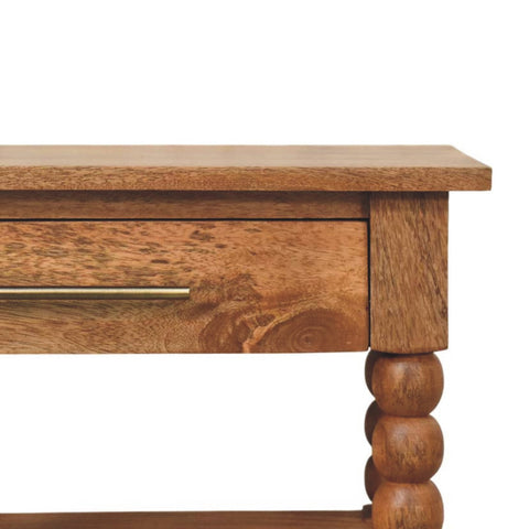 Rustic spindle side table with warm brown golden teak finish, single drawer with brass handle, and turned bead legs