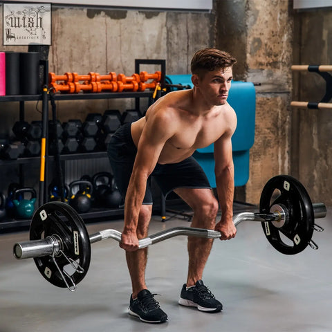 A man lifting a silver barbell with black sportnow 5kg weight plates in a gym for strength training