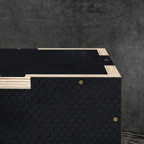 Black wooden jump box with hexagonal pattern, light wood trim, and brass fasteners for home and gym use