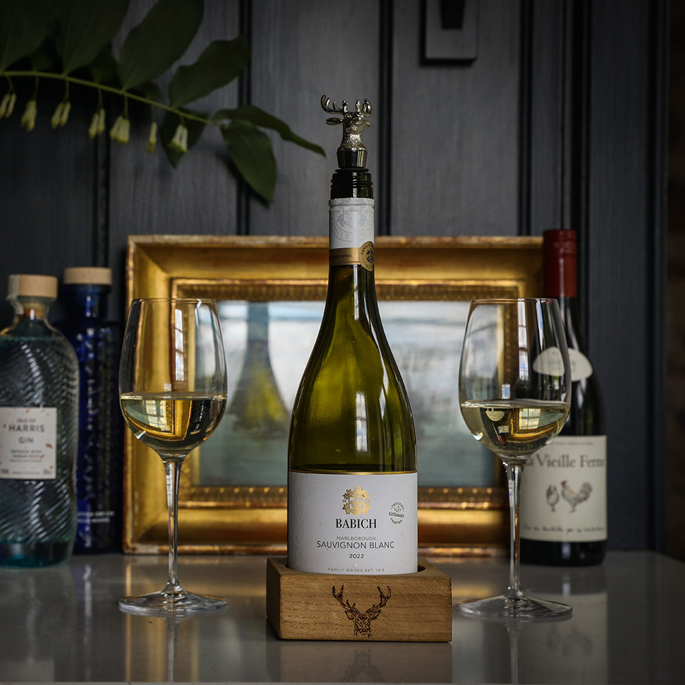 Green glass bottle of babich marlborough sauvignon blanc 2021 with silver deer bottle stopper on wooden stag block gift box