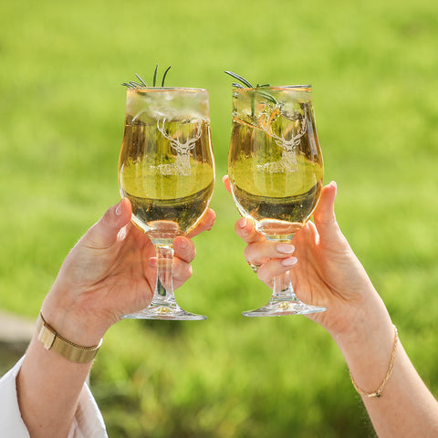 Clear glass stag craft beer glasses set of 2 with etched deer designs filled with golden craft beer and rosemary sprigs