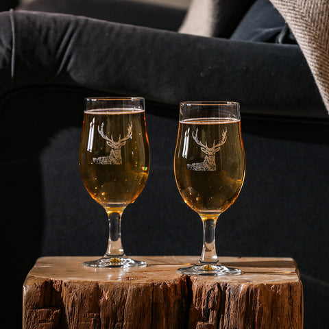 Two clear glass stag craft beer glasses featuring white etched stag design filled with golden bubbly craft beer