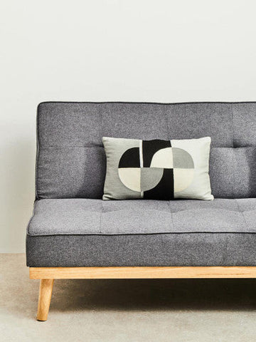 Stockholm 3 seat grey sofa bed with tufted grey fabric, light wood legs, and geometric-patterned accent pillow