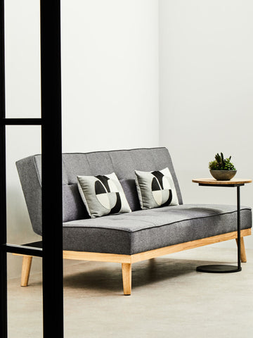 Modern stockholm 3 seat grey sofa bed with grey fabric, light wood legs, and two black and white abstract pillows