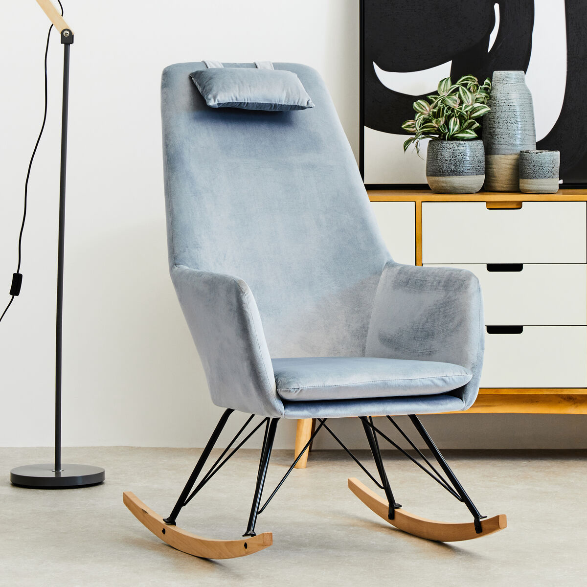 A sleek stockholm blue velvet rocking chair with cushioned headrest wooden rockers and black metal legs