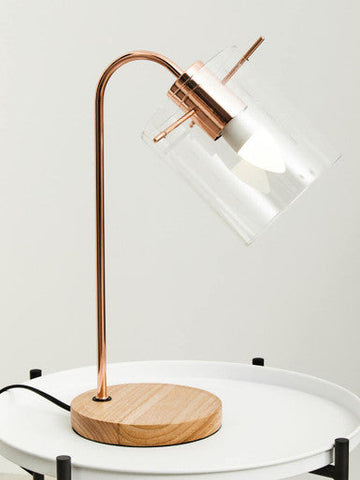 Stockholm shiny copper desk lamp with shiny copper curved arm, clear glass shade, and wooden base for stylish lighting