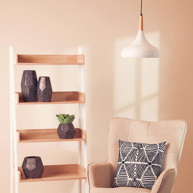 Beige armchair with black and white geometric cushion under a white curved pendant light for cozy living spaces