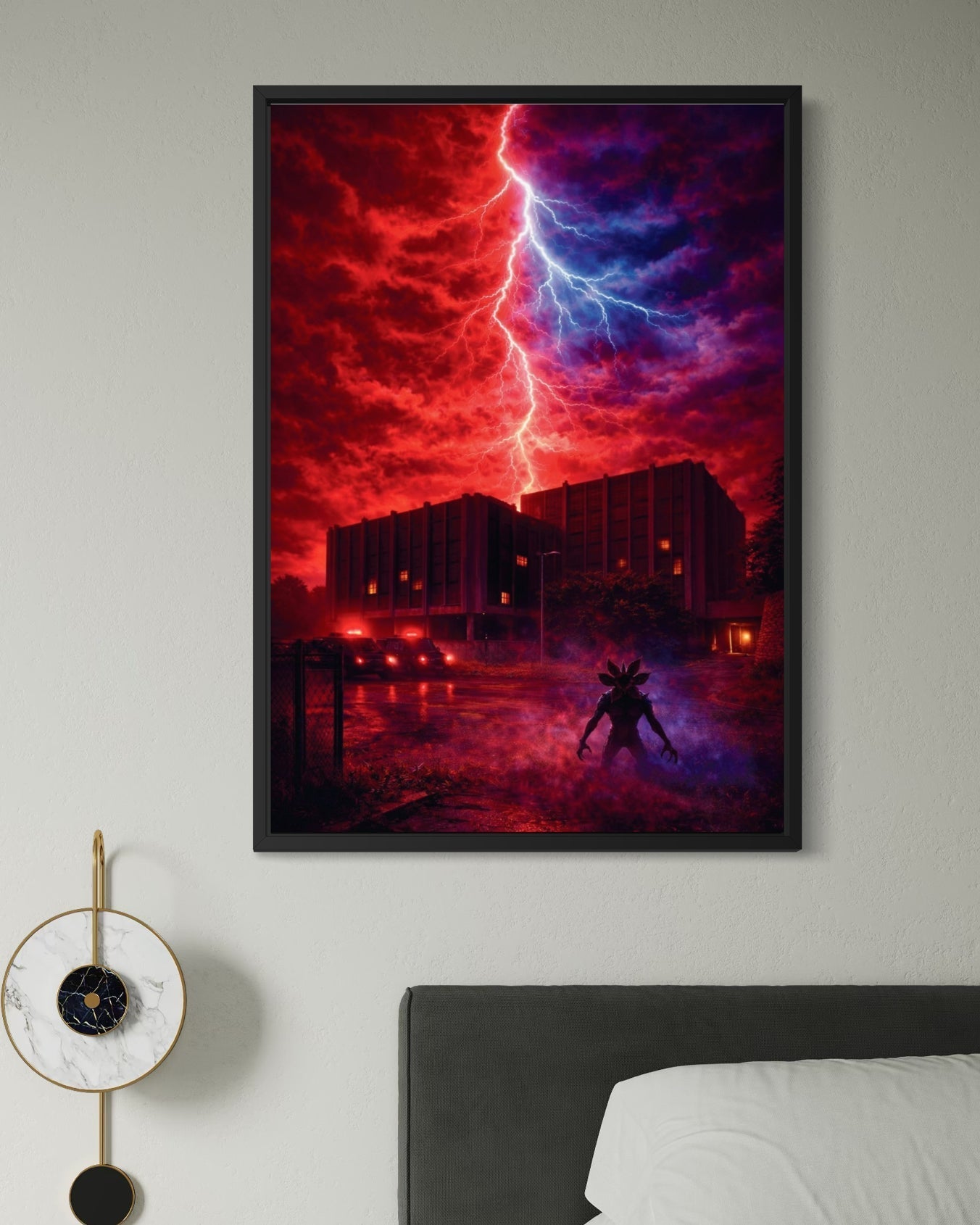 A framed stranger things poster showing red and blue lightning striking over a building with a silhouetted figure