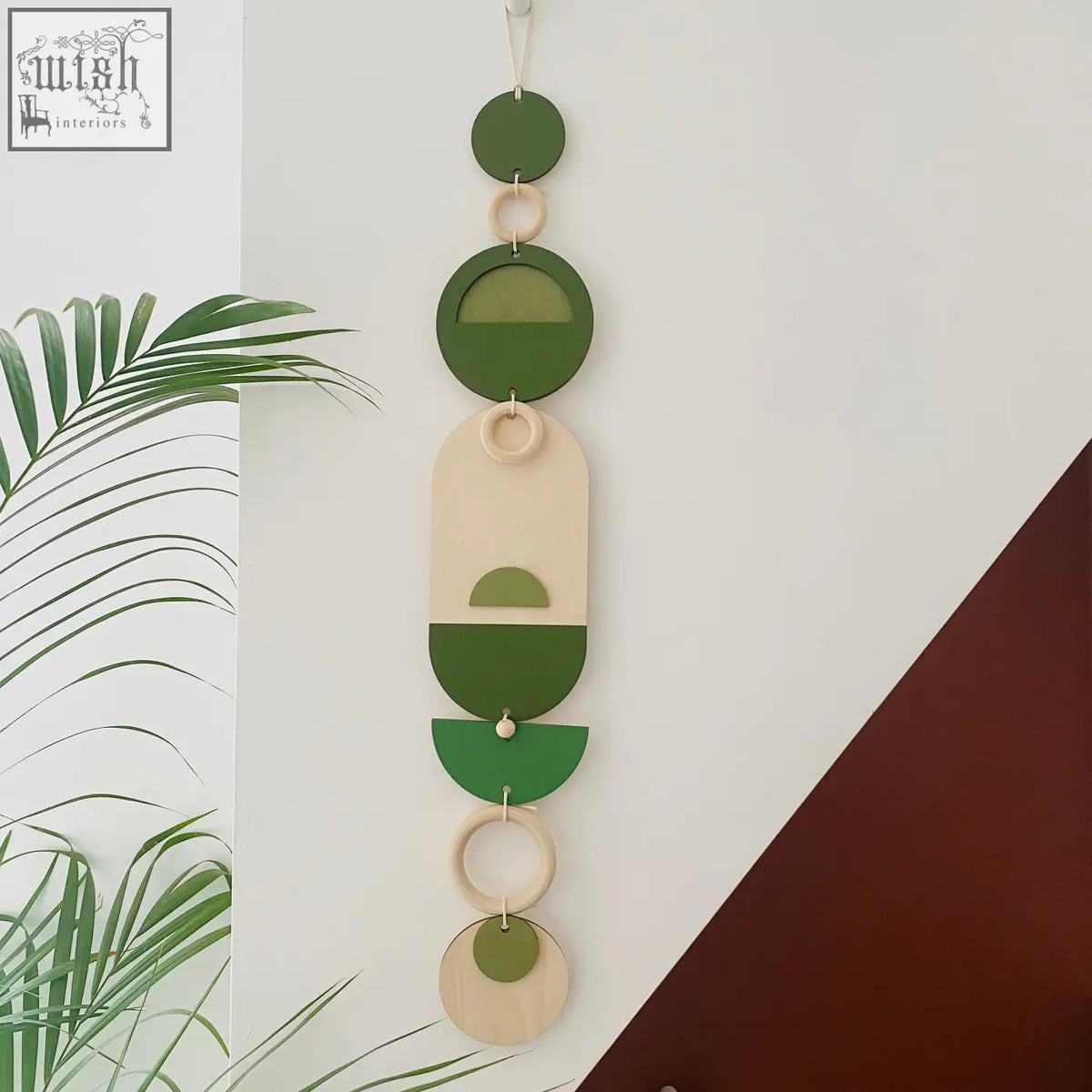 A modern green geometric wall art made of layered wooden circles and rings for minimalistic home decor