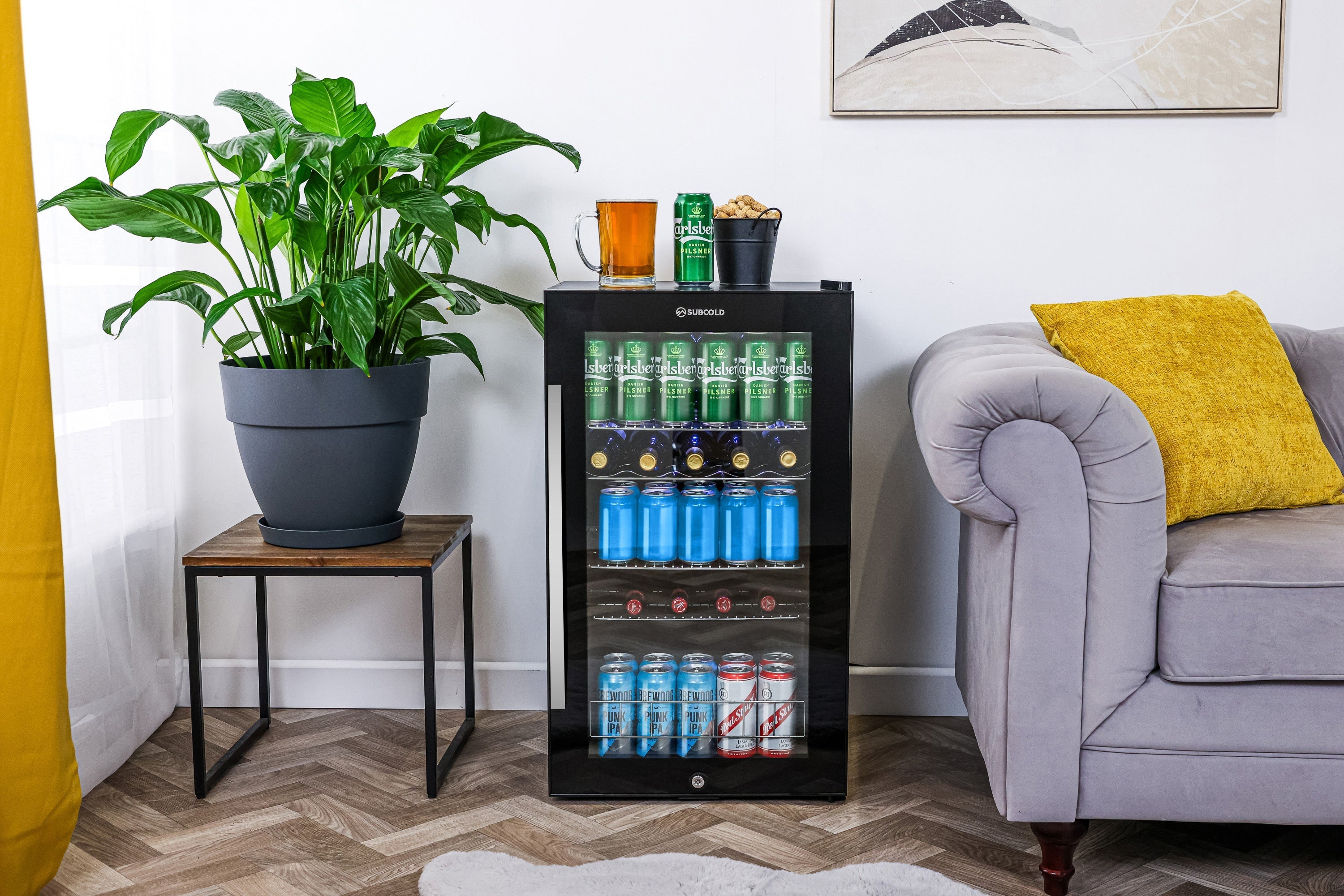 Black glass-door subcold ace100 beer fridge with silver trim and shelves holding canned drinks for easy chilling