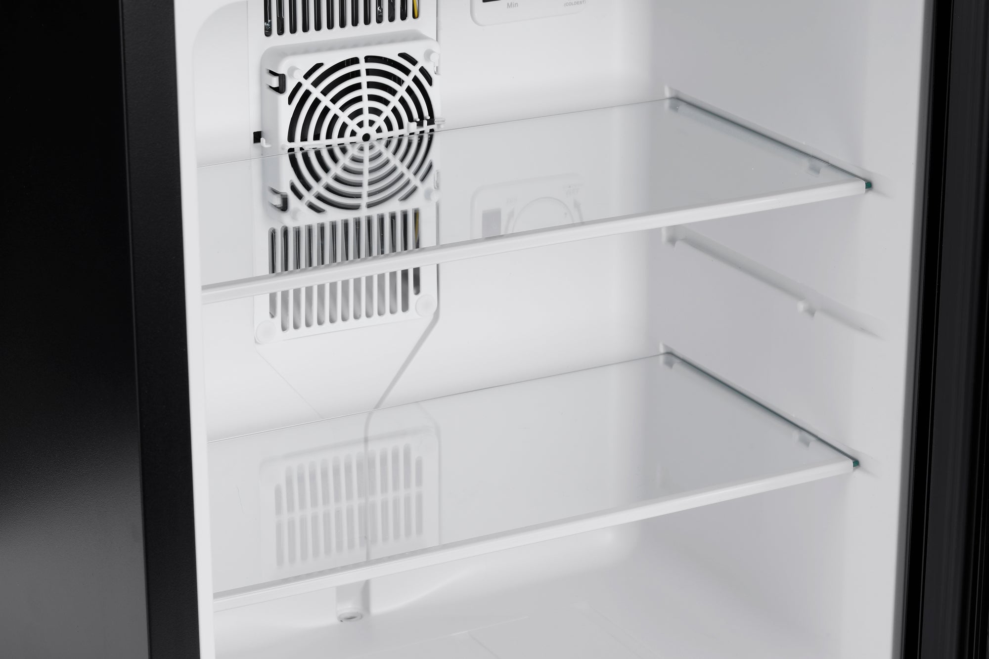 White interior of subcold aire30-g mini fridge with clear glass shelves and a white fan unit inside