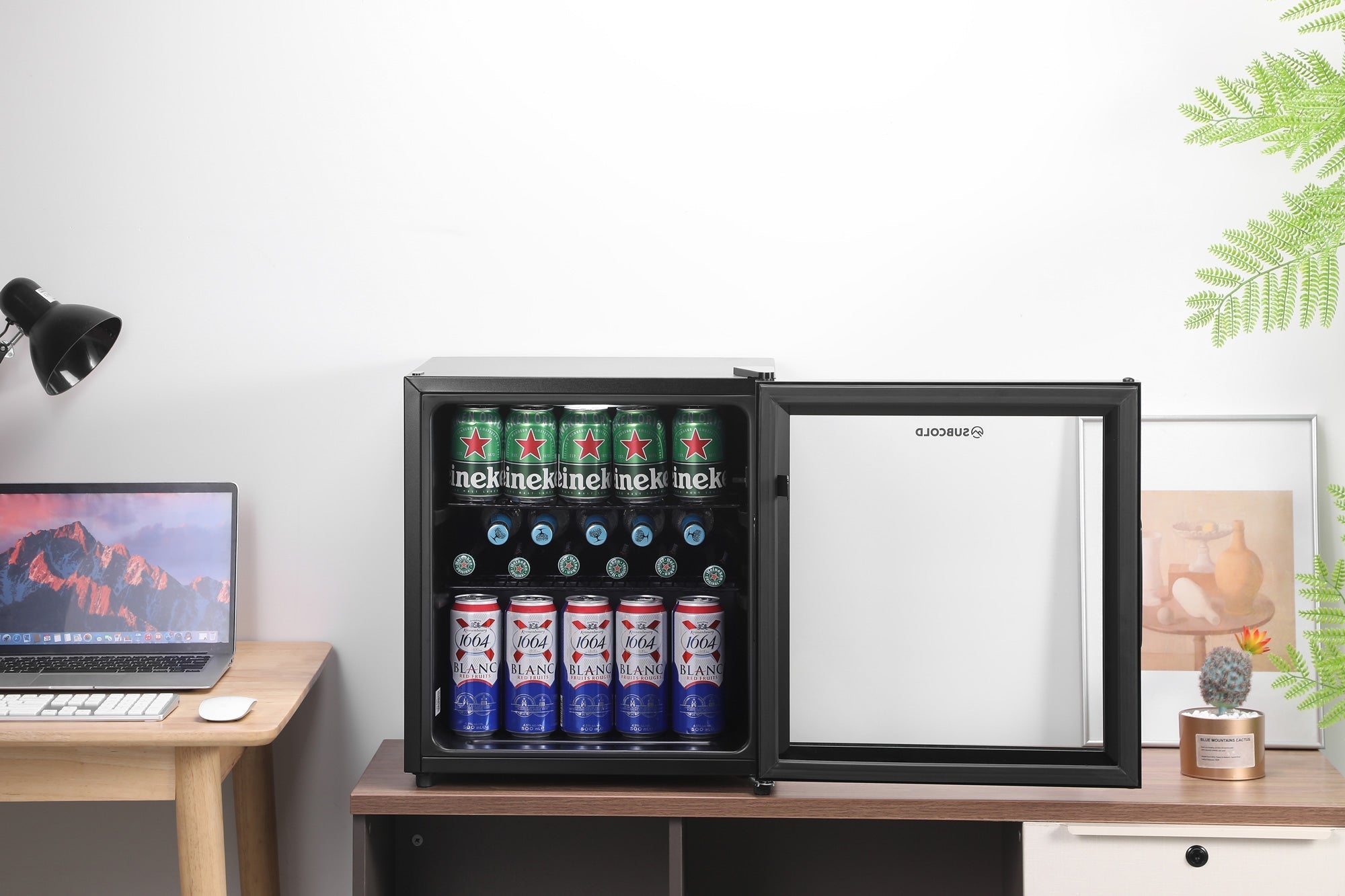 Black-framed Subcold Cave50 glass door beer fridge with silver interior stocked with Heineken and Budweiser cans