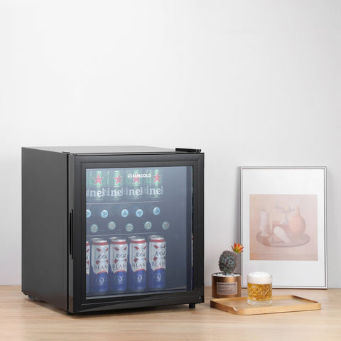 Black subcold cave50 glass door mini fridge with sleek design showing neatly arranged beer cans and soft drinks inside