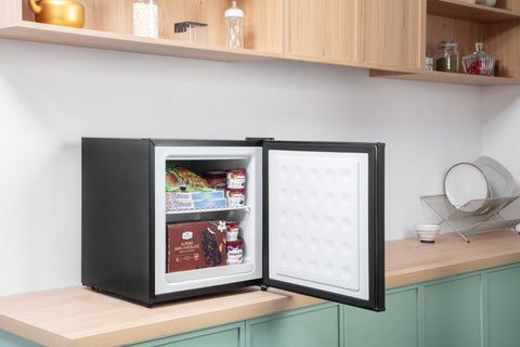 Black subcold eco35f mini freezer with white interior and textured door panel stocked with frozen food items