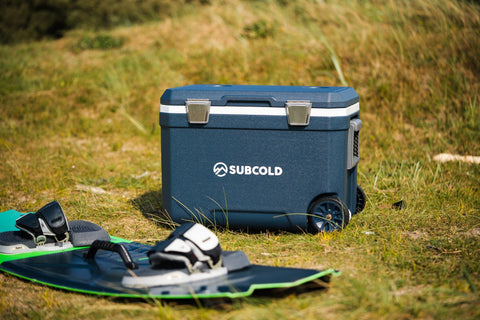 Blue subcold mobi45 cool box with silver latches and wheels sitting on grass beside wakeboard gear