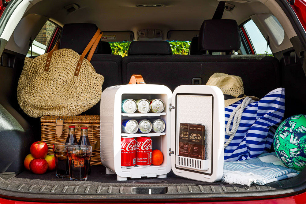 White Subcold Pro 10L mini fridge with open door showing canned drinks and chocolate bars inside compact 10l mini fridge