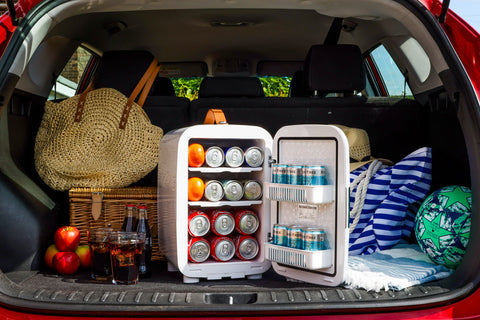 White subcold pro 15l mini fridge with open doors showing canned drinks and oranges inside for compact storage