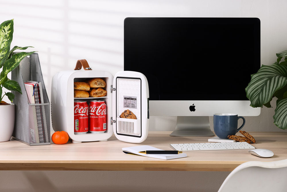 White compact subcold pro 4l mini fridge with brown leather handle and shelves holding cookies and coca-cola cans
