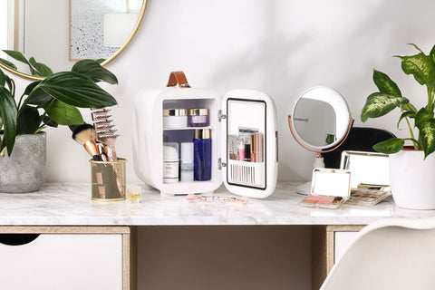 White subcold pro 4l mini fridge with brown leather handle and interior shelves holding beauty products