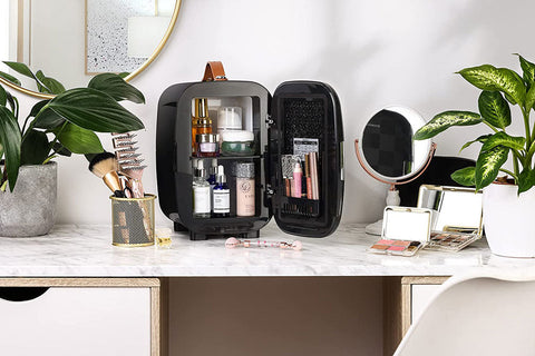Black subcold pro 6l mini fridge with brown leather handle and removable shelf holding larger beauty products