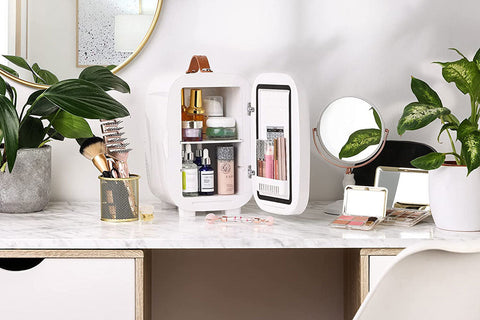 White subcold pro 6l mini fridge with brown leather handle and removable shelves storing beauty products and larger items