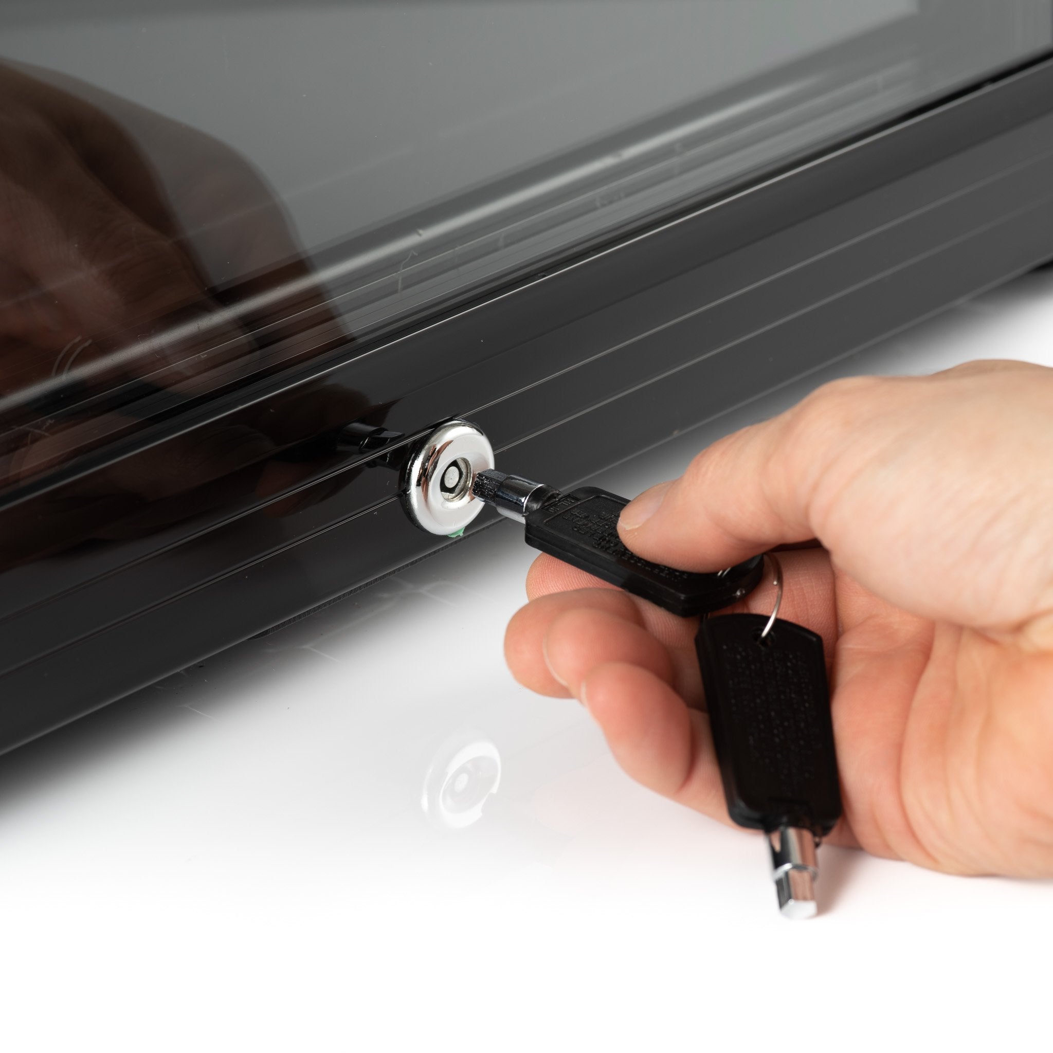 Black key with silver lock being inserted into sleek dark gray subcold super65 drinks fridge for secure access