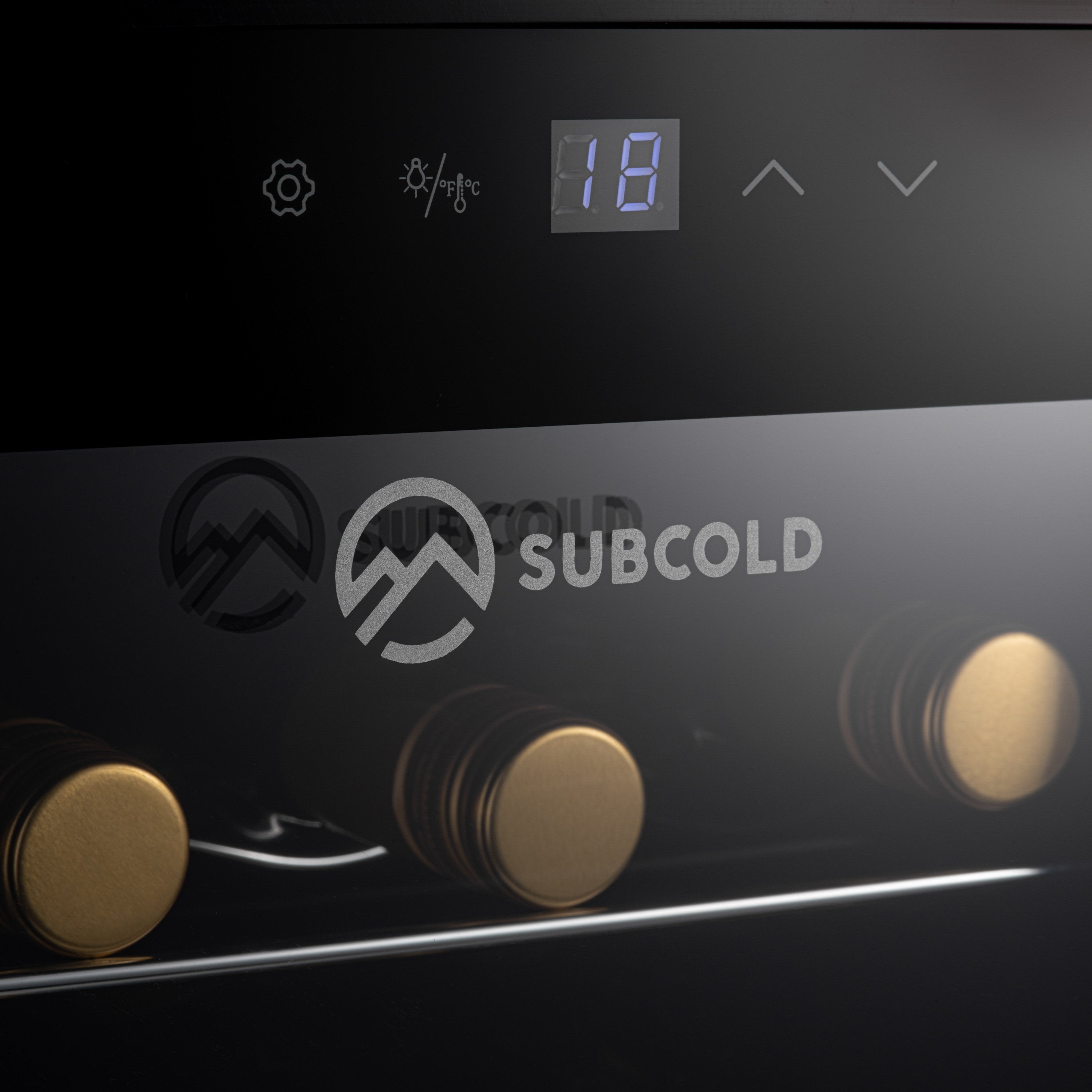 Black subcold viva24 led wine cooler with gold-tone knobs and digital display showing 18 degrees