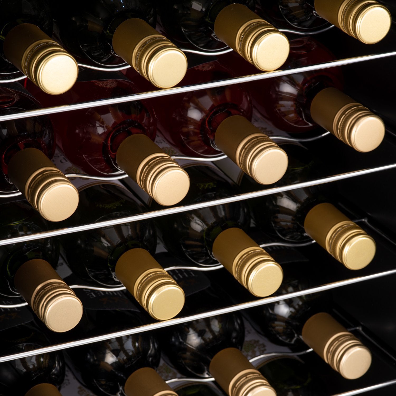 Rows of dark glass wine bottles with gold foil caps stored in a subcold viva28 led wine fridge with silver racks