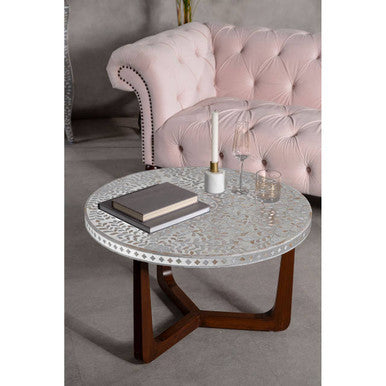 Round coffee table with white patterned top and dark wood legs paired with a blossom fabric chesterfield sofa