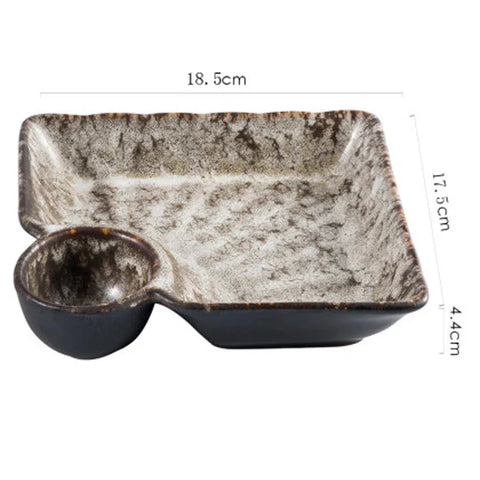 A rustic ceramic sutekina plates serving tray with speckled gray and black glaze and a built in small bowl on one side