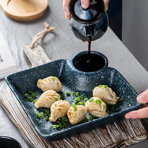 Dark blue speckled ceramic sutekina plates holding steamed dumplings garnished with chopped green onions