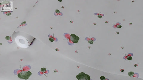 A roll of sweet clover wallpaper in light gray with pink and purple butterflies and green three leaves made of ethically sourced materials