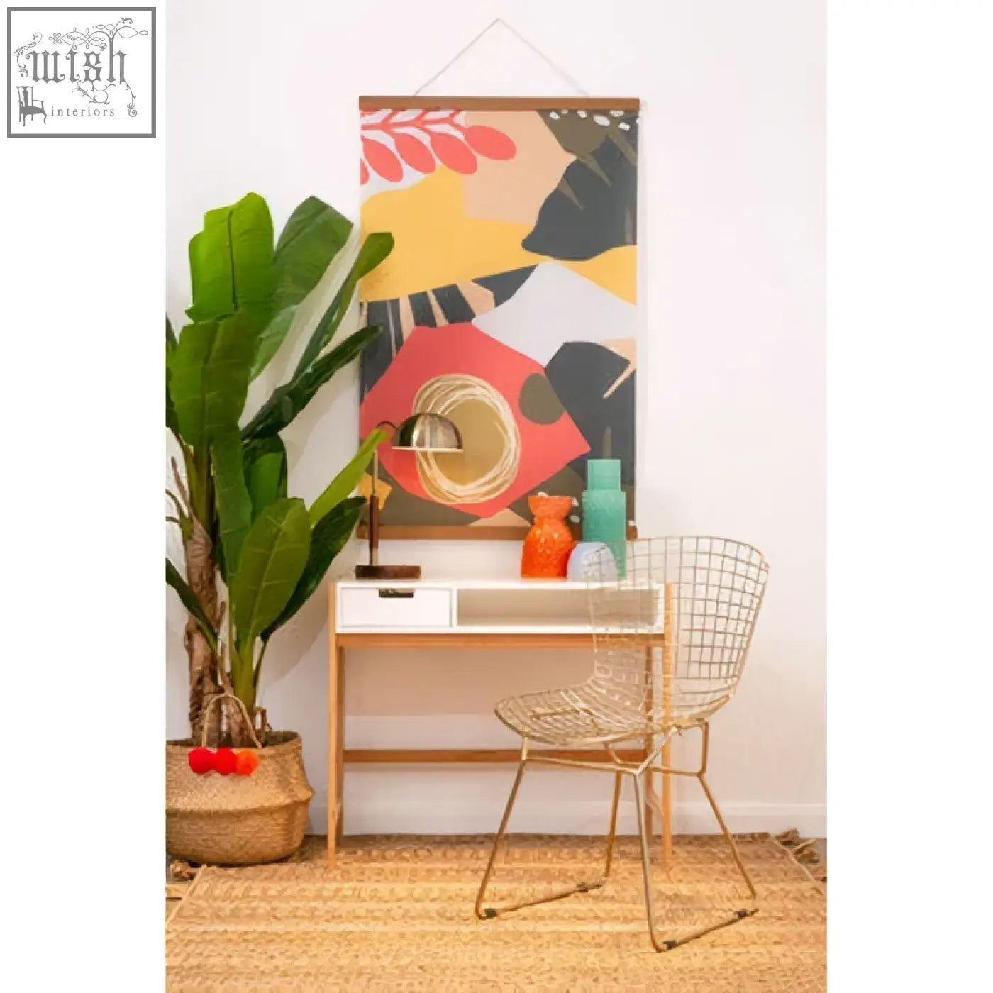 The sydnee brass finish task lamp with wood base shines beside a vibrant red yellow and black leaf wall hanging