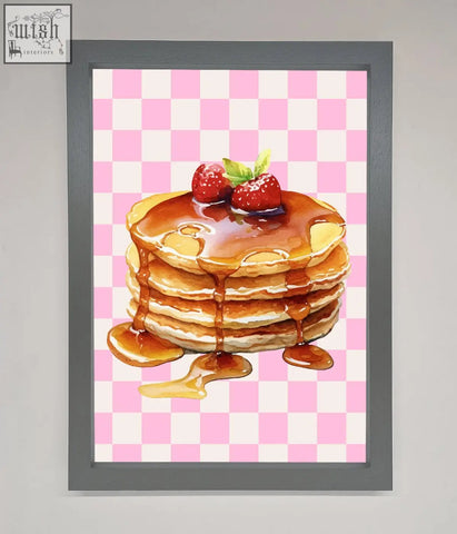 A framed print of syrup pancakes with vibrant colors topped with strawberries on a pink checkered background