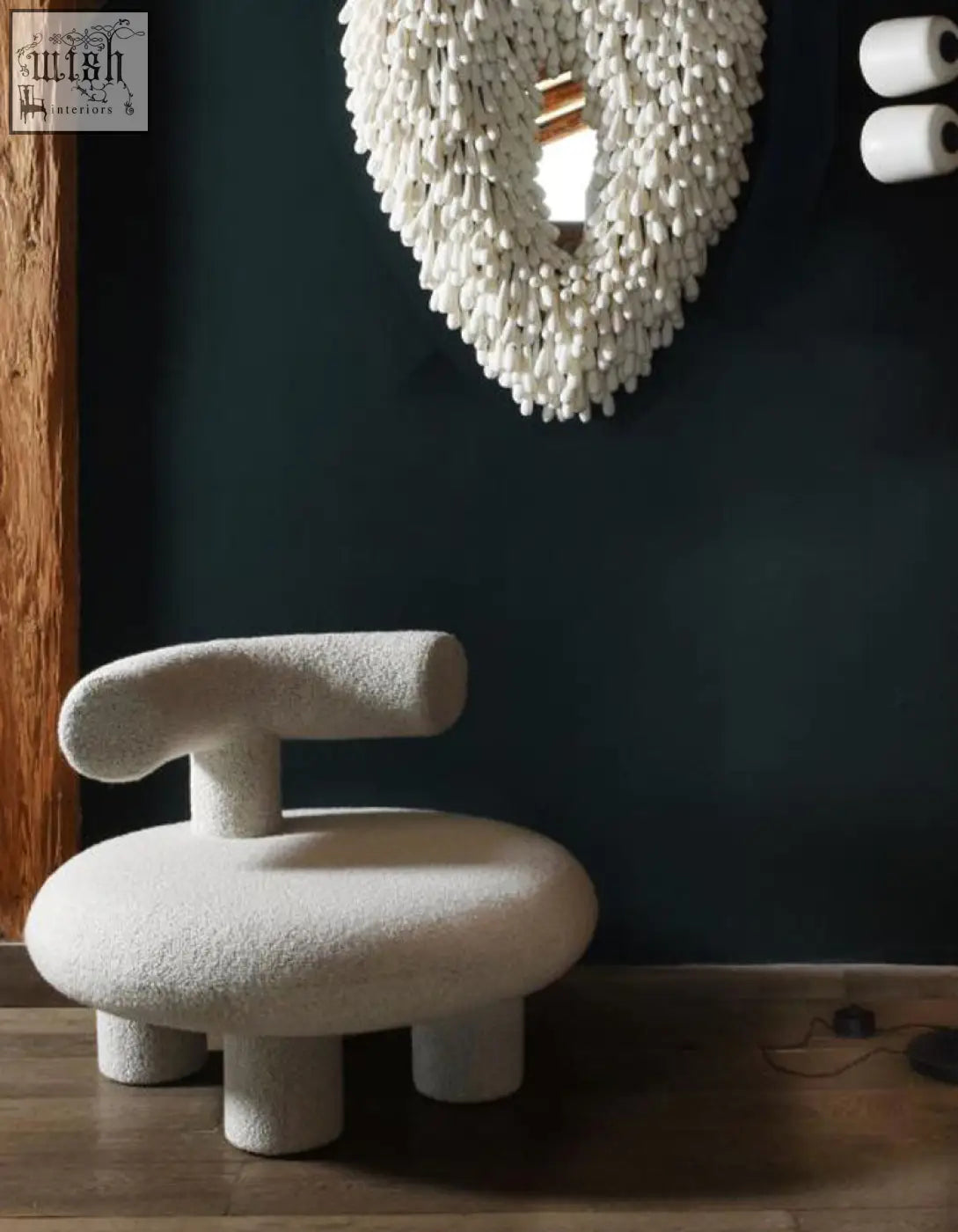 Cream-colored cashmere wool shapte sheep armchair with plush texture and rounded minimalist design and cylindrical legs