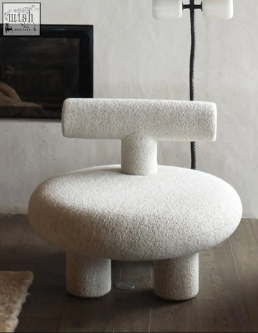 A plush off-white t shapte sheep armchair with textured cashmere wool upholstery and rounded seat on short legs